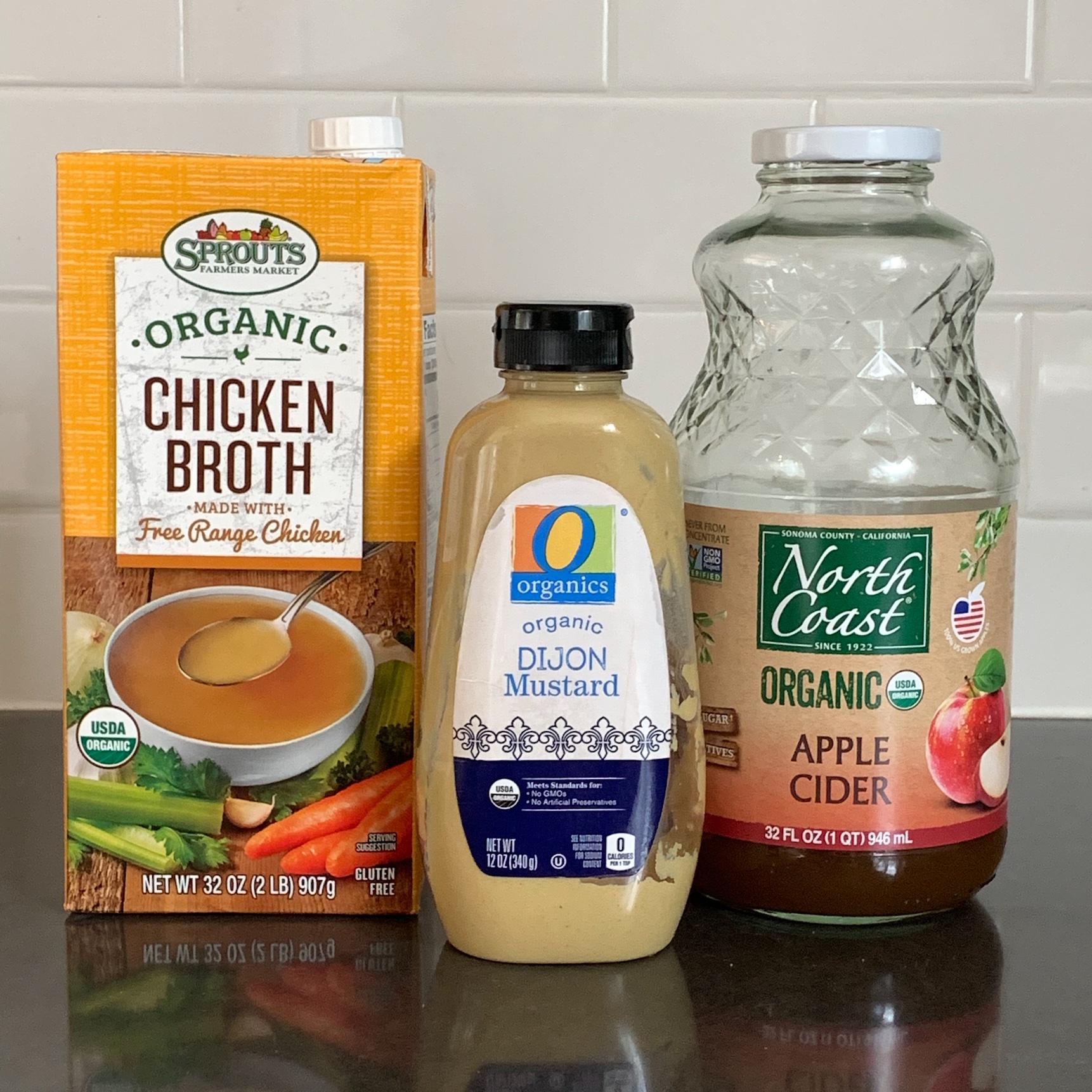 Chicken broth, apple cider, and dijon mustard in bottles