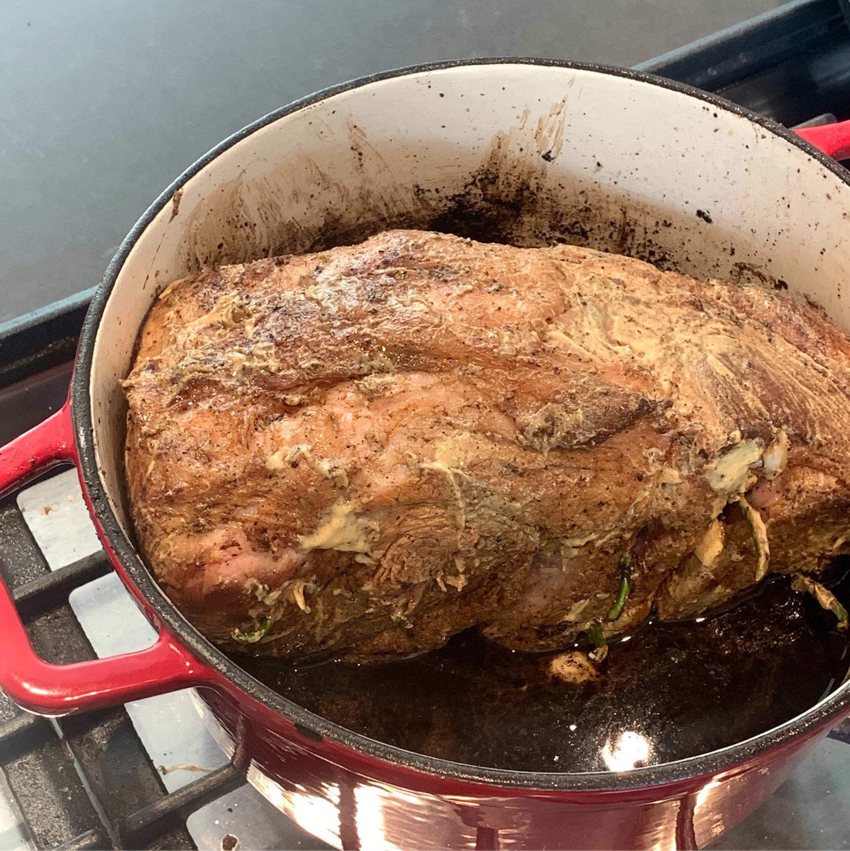 prepared pork shoulder put back in the dutch oven and braising liquid